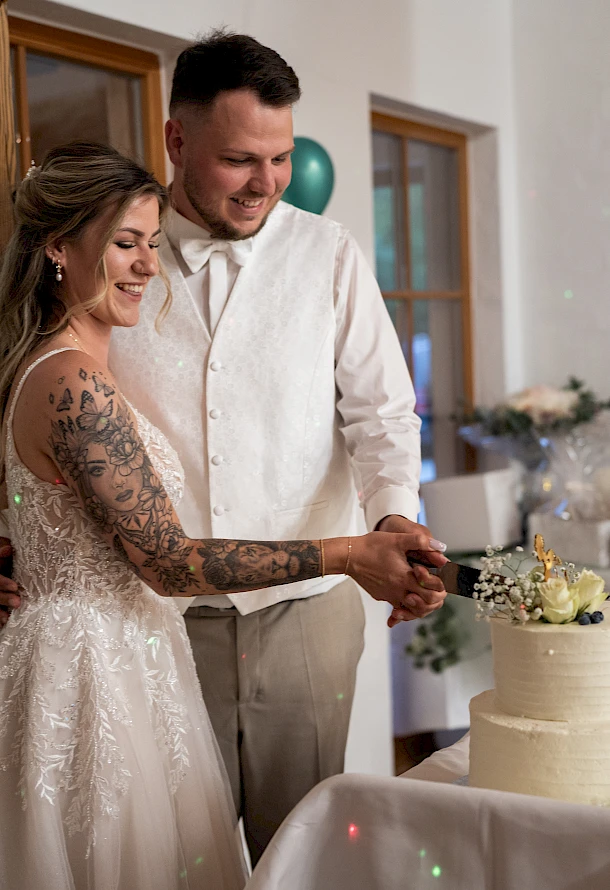 Braut und Bräutigam schneiden ihre Hochzeitstorte während der Hochzeitsfeier an